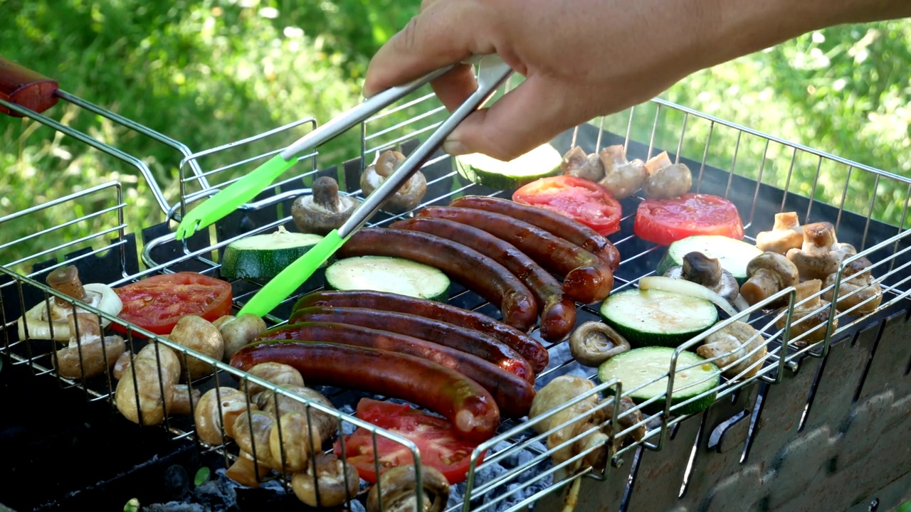 在烤架上烤。室外烤架上的油炸香肠和蔬菜。B-B-Q。油炸食品是在木炭烤架上油炸和烟熏的。原来是一个烤炉，里面有美味的香肠，蔬菜，香菇。野餐和露营街头食物视频素材