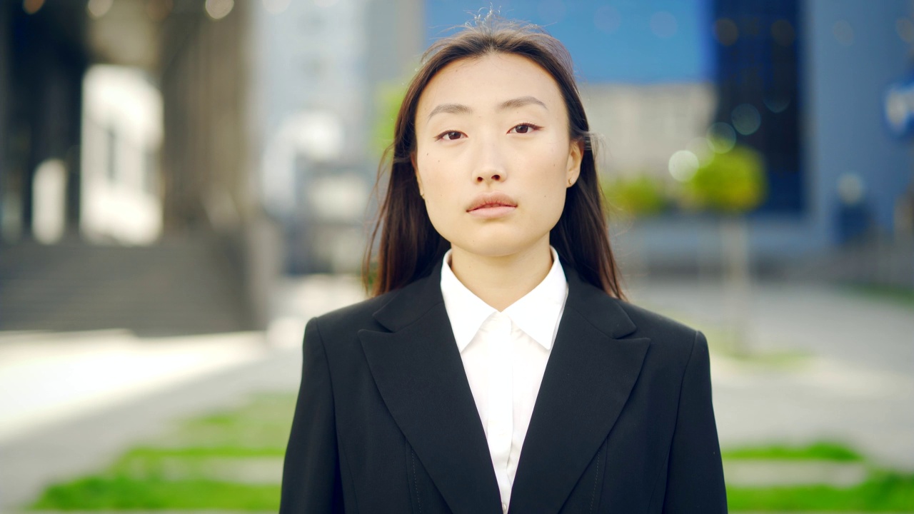 特写肖像年轻有吸引力的亚洲商业女性看相机在城市城市街道的背景。面对独立自信的女商人或学生。外视频素材