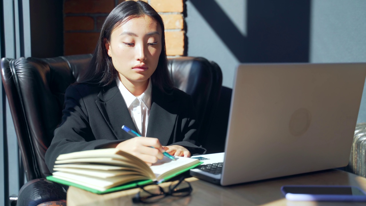 年轻的女性自由职业者或在线工作或在咖啡馆远程学习的学生。亚洲商业女性西装使用打字笔记本电脑在工作的共同工作热办公桌视频素材