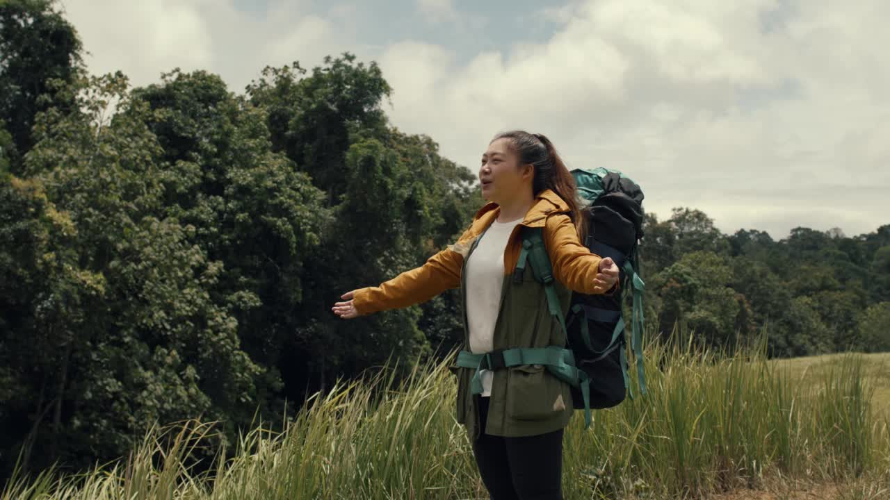 泰国森林徒步旅行的年轻女子。背着背包的活跃健康的女人。女性旅行者与漫步森林后视图，休闲，生物旅游，徒步旅行。她是快乐的。视频素材