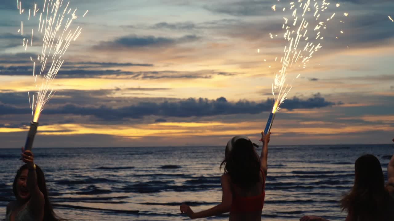 4K一群亚洲女人在夏夜的热带海岛海滩上一起玩烟火。视频素材