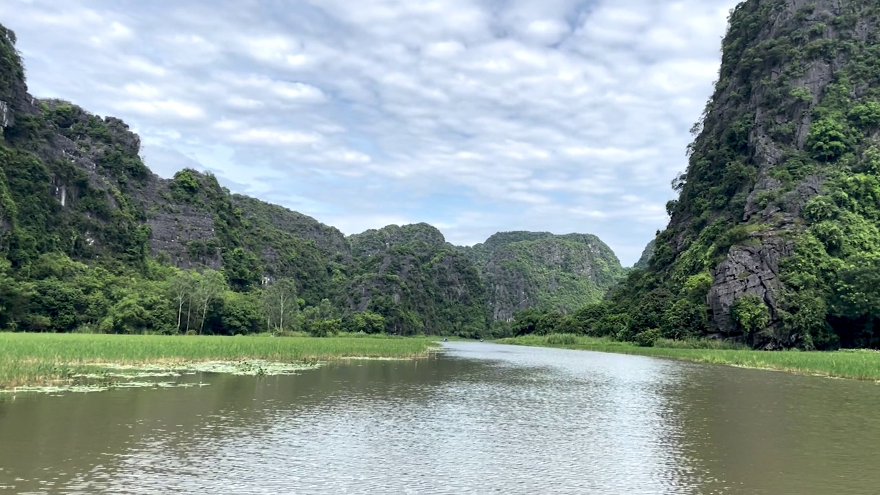 在越南北部的宁平省，美丽的Tam Coc洞穴和湖的船视图，在炎热的夏天，有令人惊叹的山脉，岩石和稻田。视频下载