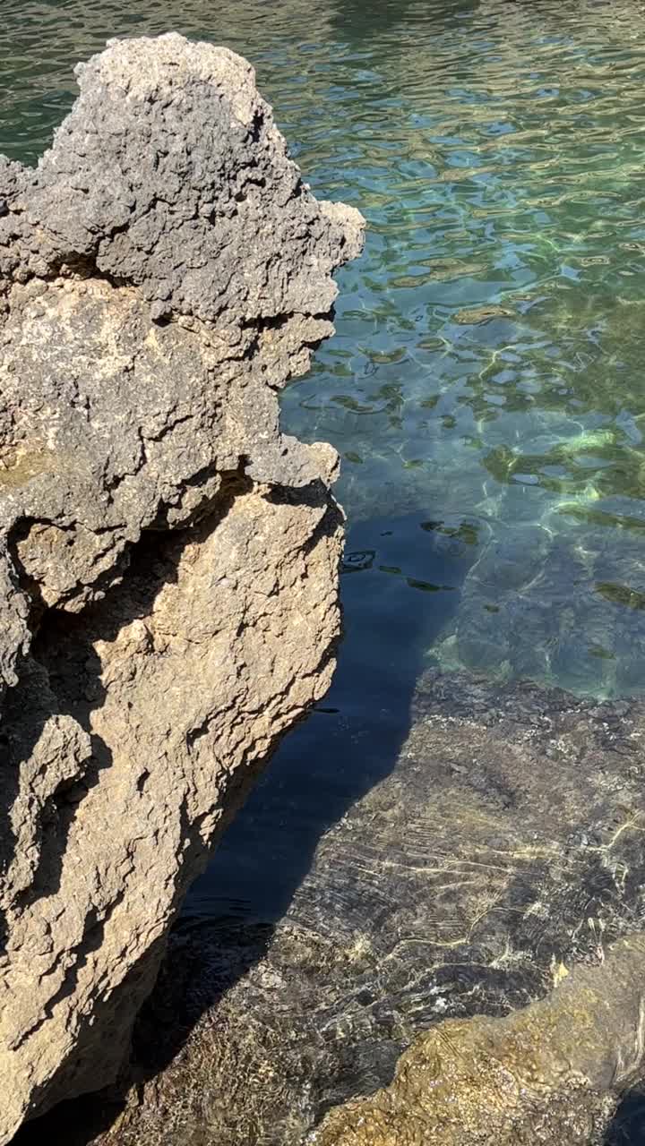 悬崖映衬着绿松石般的海水。美丽的岩石海岸。视频素材