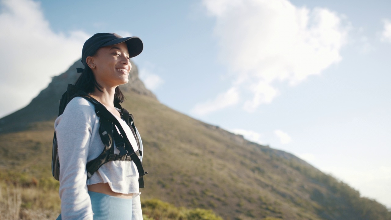 美丽的混血女子放松在田野上的山，而外出徒步旅行。拉丁女徒步旅行者在探索自然和伟大的户外时，在山顶休息和享受景色视频素材