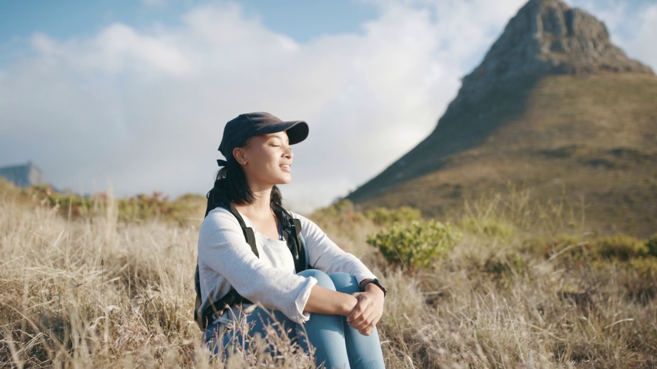 美丽平静的女人放松和呼吸新鲜空气的田野在山上远足。女徒步旅行者在探索自然和户外的同时休息和享受风景视频素材