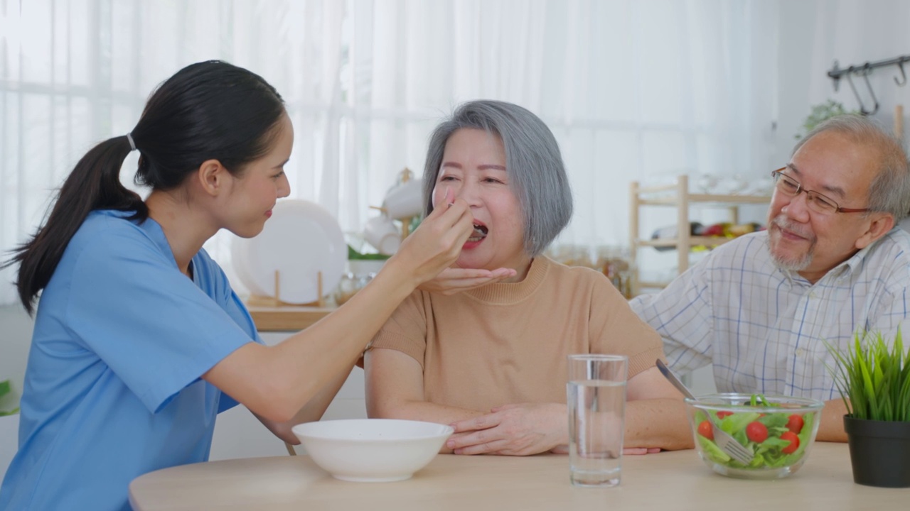 亚洲护工护士为有丈夫的老年女性病人提供食物。有魅力的年轻专家护理女医生支持和照顾快乐的老人老人成熟的祖母为健康在家里。视频素材