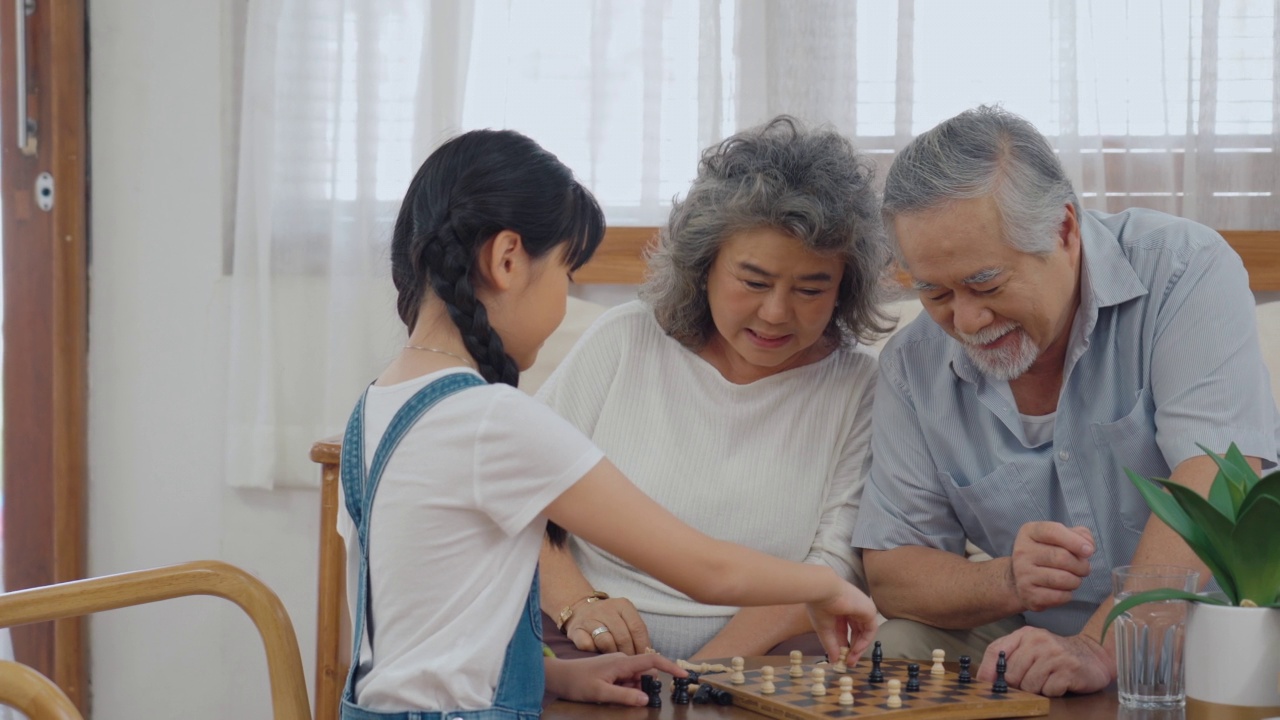 老夫妇和孙女在家里下棋，一起享受视频素材