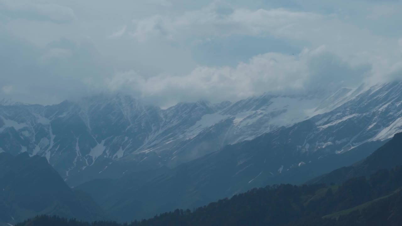 从印度喜马偕尔邦的马纳利看，季风期间，积雪覆盖的喜马拉雅山脉上乌云密布。在雨季的暴风雨天气里，云层覆盖着山峰。视频素材