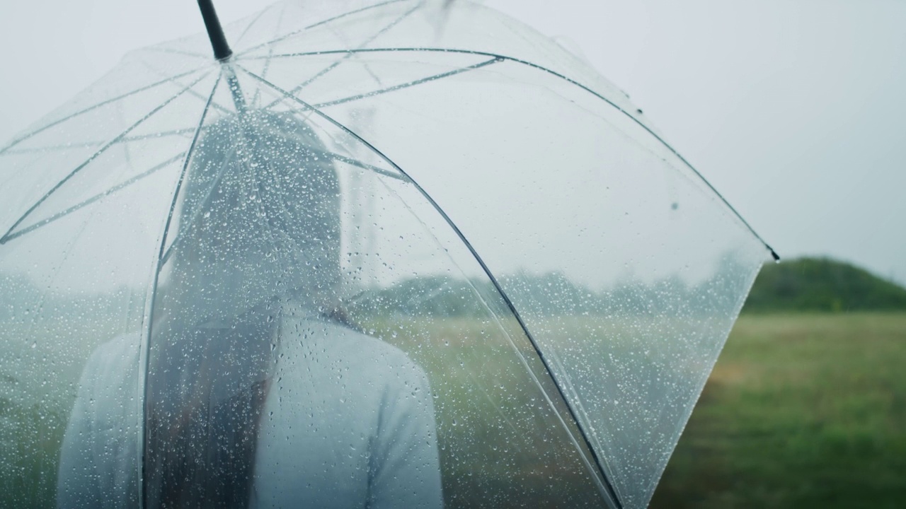 一个悲伤的亚美尼亚女人撑着伞在雨中行走。她喜欢这种天气。视频素材