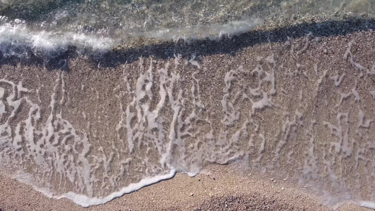 鸟瞰图，美丽的沙滩上有脚印和柔和的蓝绿色海浪。莱夫卡达岛凯西玛海滩夏季的热带海洋。视频素材