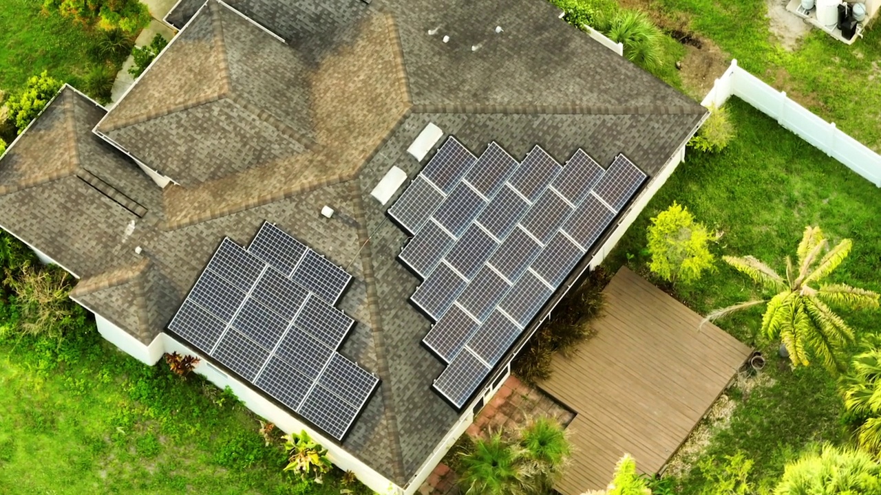 位于郊区农村的屋顶覆盖太阳能光伏板的住宅，用于生产清洁的生态电能。自主家居的概念视频素材