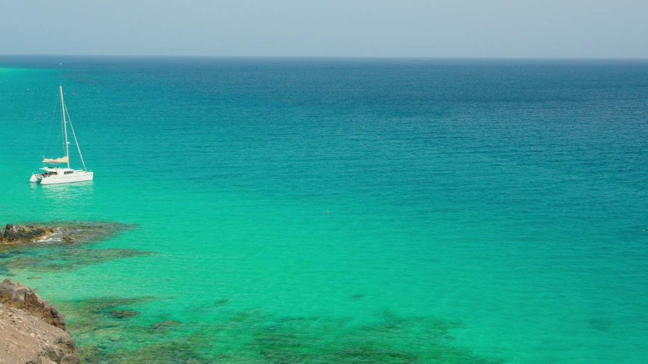 美丽的海洋海岸线和平静放松静观翡翠的海水大海。自然景观令人心旷神怡，容易入眠。白色的帆船漂浮在波浪上。视频素材