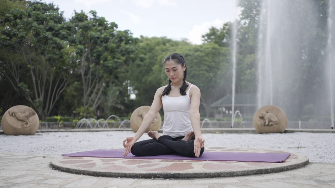 亚洲妇女在公园里做瑜伽。视频素材