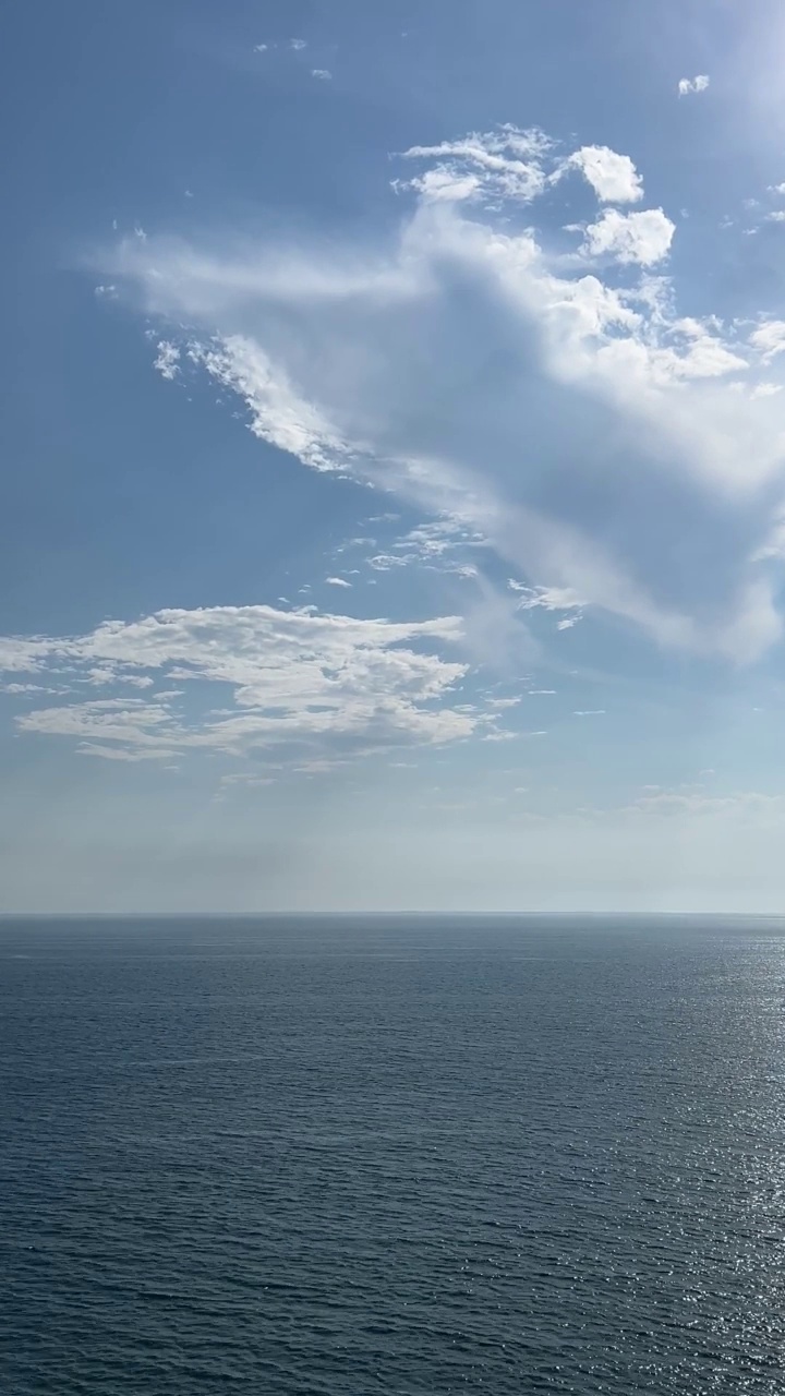 闪闪发光的蓝色银色海浪的岩石海岸线。夏日海面上美丽的云朵。视频素材