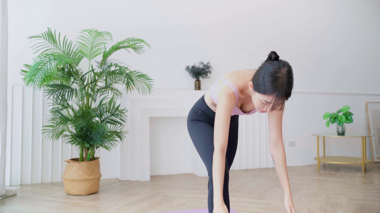 年轻微笑迷人的运动亚洲女性练习瑜伽，做Virabhadrasana 1练习，在勇士1瑜伽姿势冥想，在家室内锻炼，穿着运动服。实时4k视频视频素材