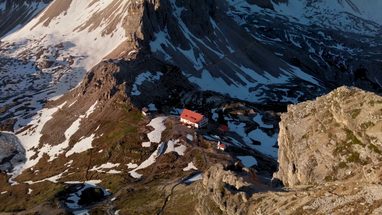 在日出时分，意大利塞克斯滕白云石的Tre Cime di Lavaredo国家公园的Dreizinnen山小屋的航拍视频素材