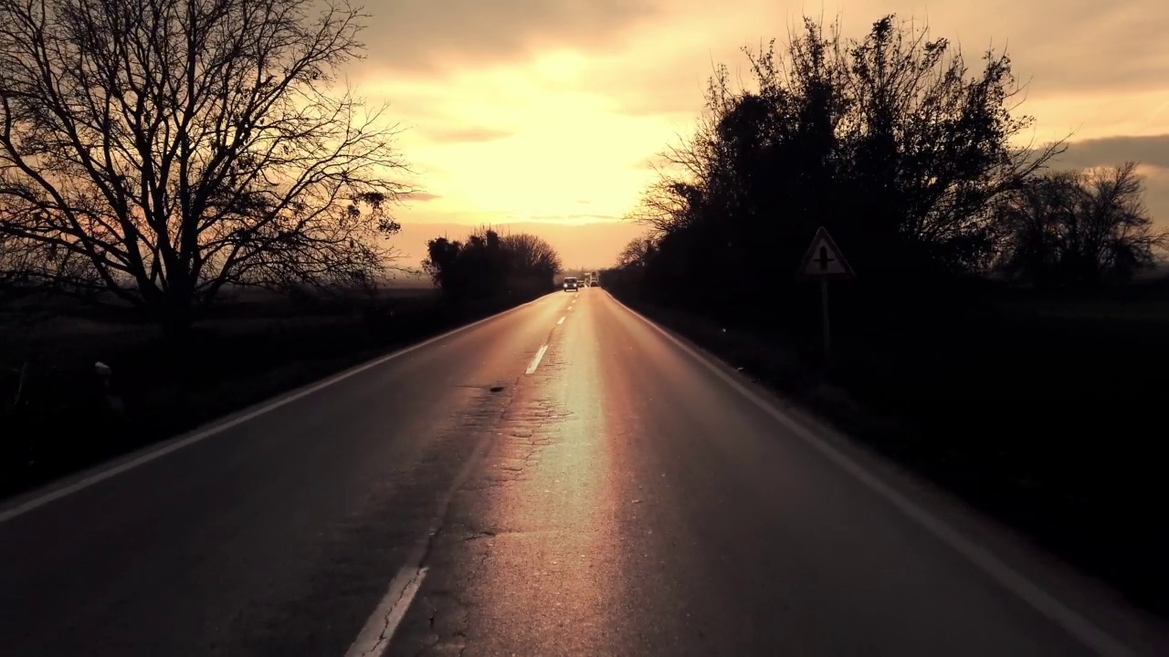 开放的乡村道路穿过绿色的田野和夕阳下的天空，司机POV视频素材