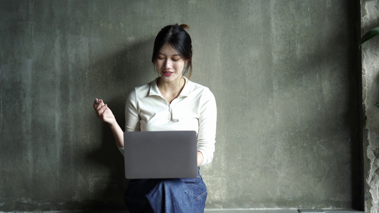 亚洲女学生通过互联网在线学习与导师在笔记本电脑上，亚洲妇女快乐的微笑打字工作，在家概念在线学习视频素材