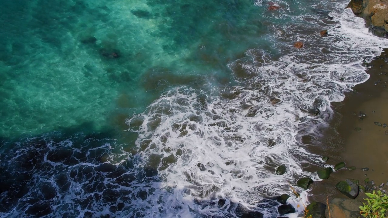 海浪拍打着布满岩石的海岸。清澈透明的海水和海底靠近海岸。视频素材