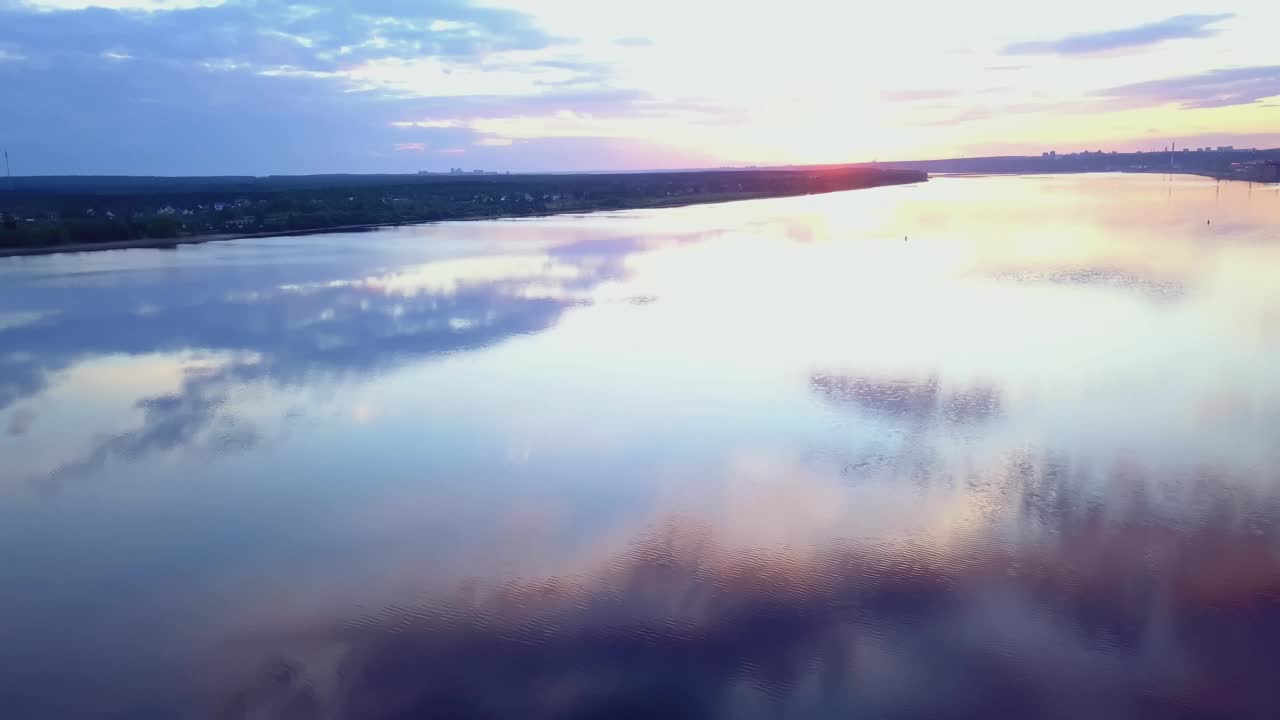 四轴飞行器在河上飞行。夹。河流景观与城市在对岸的背景下，从高空俯瞰日落视频素材