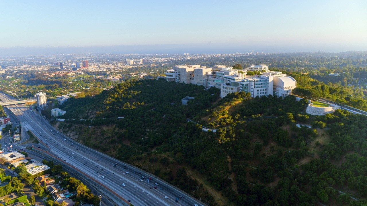 空中移动到巨大的盖蒂研究所山坡校园，前景是繁忙的高速公路-加州洛杉矶视频素材