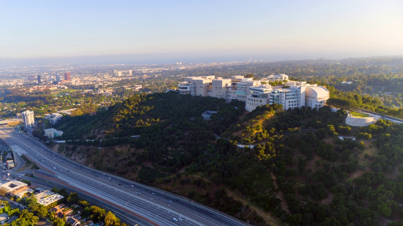 空中在盖蒂研究所山坡校区盘旋，前景是繁忙的高速公路——加州洛杉矶视频素材