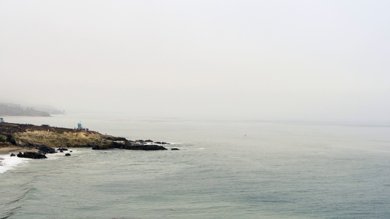 空中接近暴风雨的海岸线与撞击的波浪，灰色的天空，和人走到一个点-马里布，加州视频素材