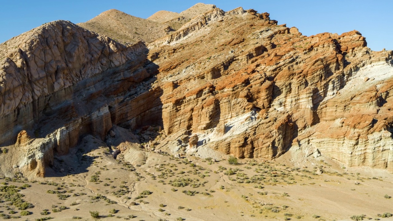 在明亮的阳光下，空中接近崎岖岩层的沉积层-加州莫哈韦沙漠视频素材