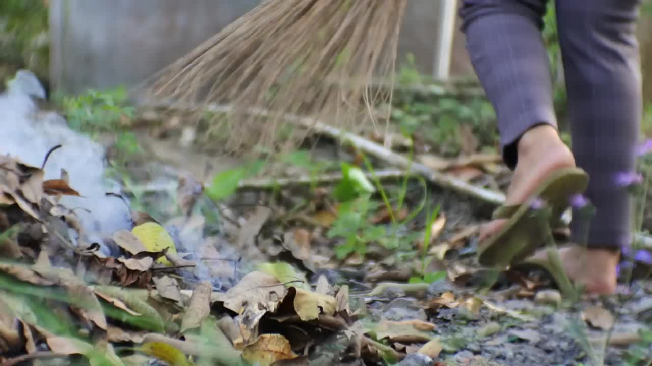 大火是由房子院子里燃烧的枯叶废料引起的。高清视频。耙干树叶，然后燃烧。视频素材