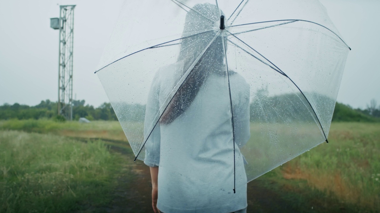 一个悲伤的亚美尼亚女人撑着伞在雨中行走。她喜欢这种天气。视频素材