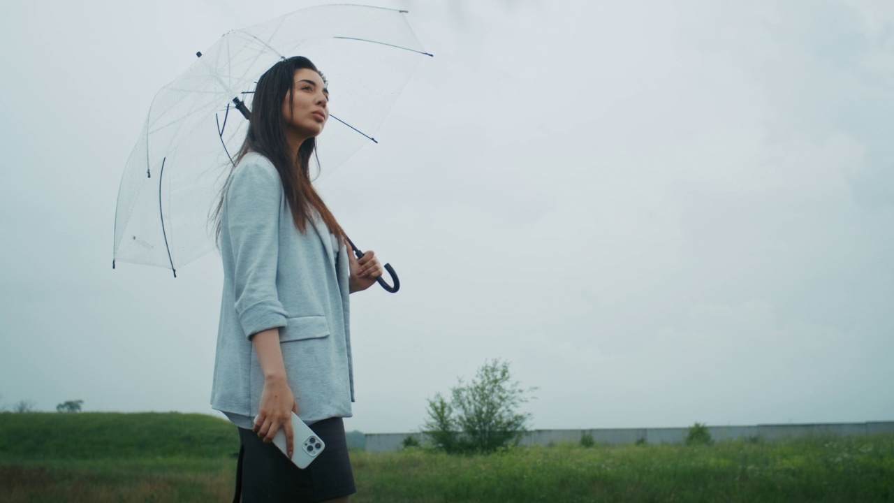 一个悲伤的亚美尼亚女人撑着伞在雨中行走。她喜欢这种天气。视频素材