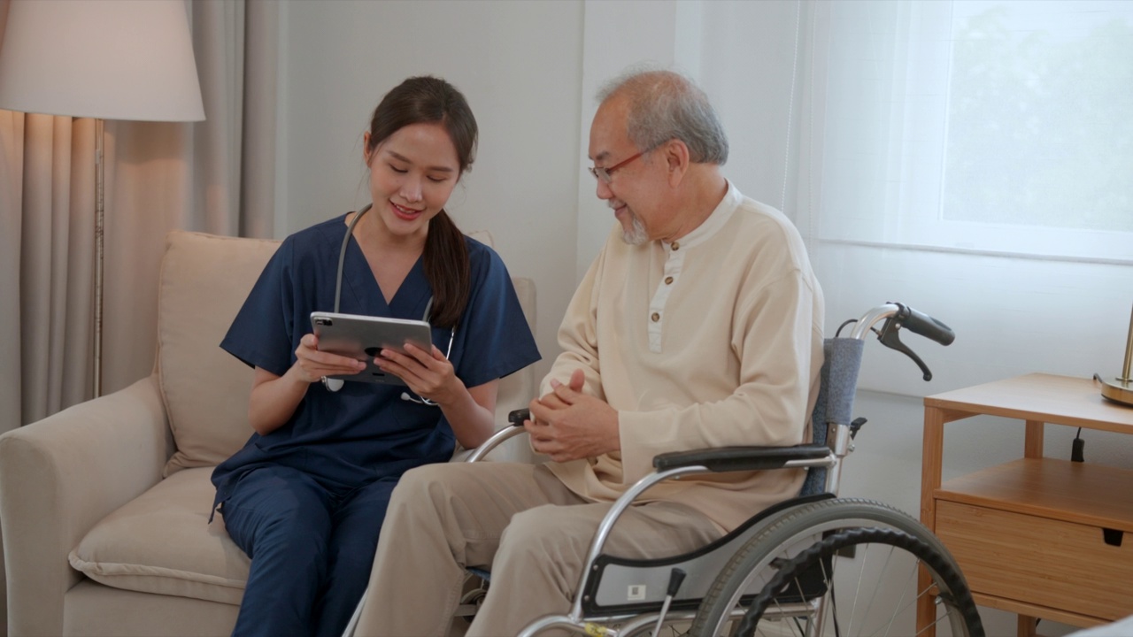 医生或护士在家里或养老院用平板电脑帮助老人视频素材