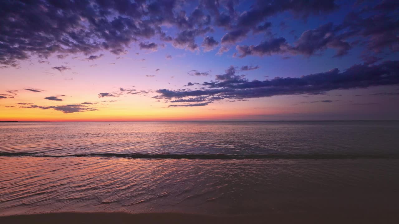 美丽的海洋沙滩日出和海沙上飞溅的波浪，自然景观的4K视频，海景视频素材