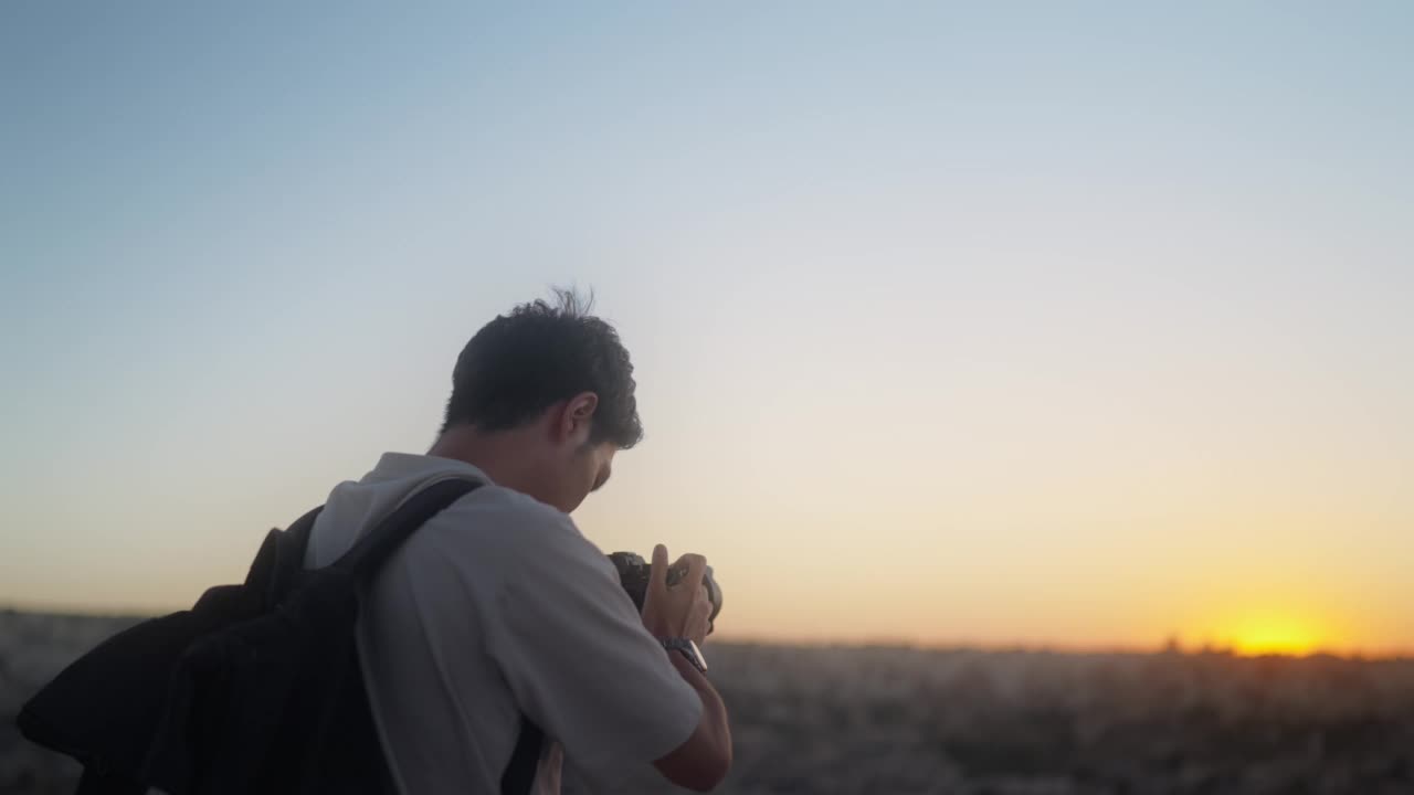 年轻的男性摄影师，摄影师，游客在日落的时候用他的相机拍摄日落的照片和视频视频素材