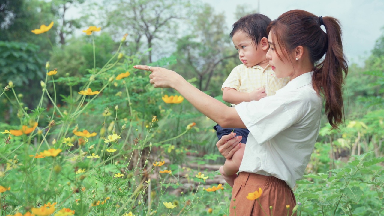 亚洲母子在公园看花。视频素材