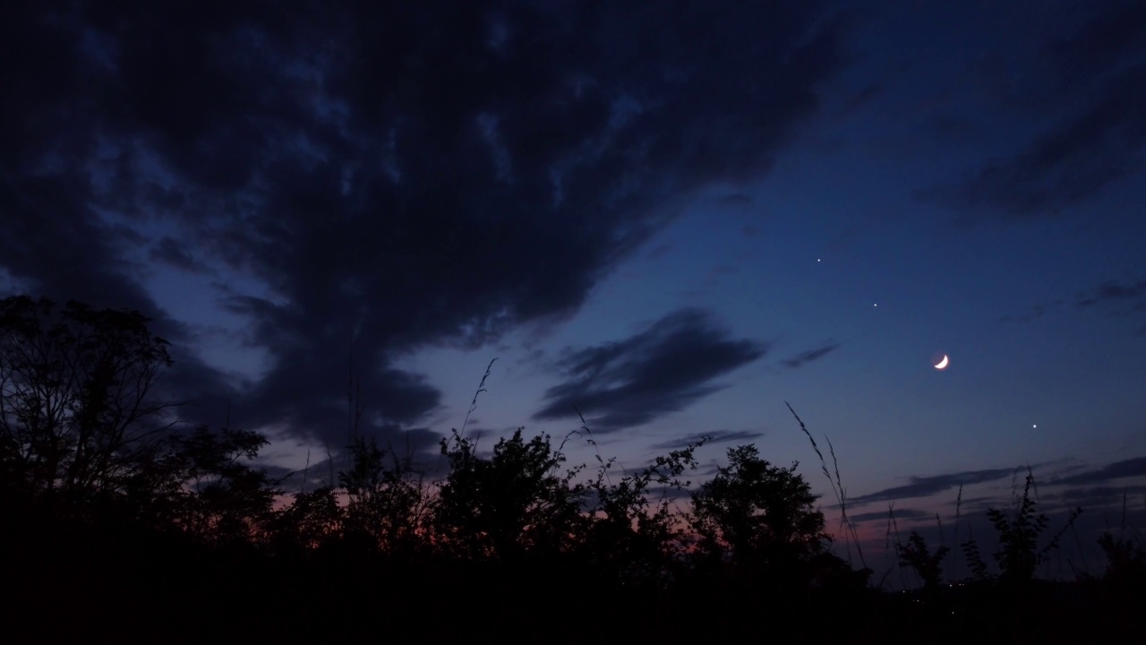 新月与星星，行星和树的轮廓在傍晚的天空。视频素材