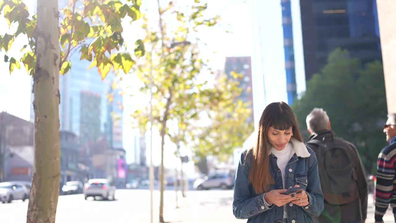 年轻女子一边走一边用手机在城市里视频素材