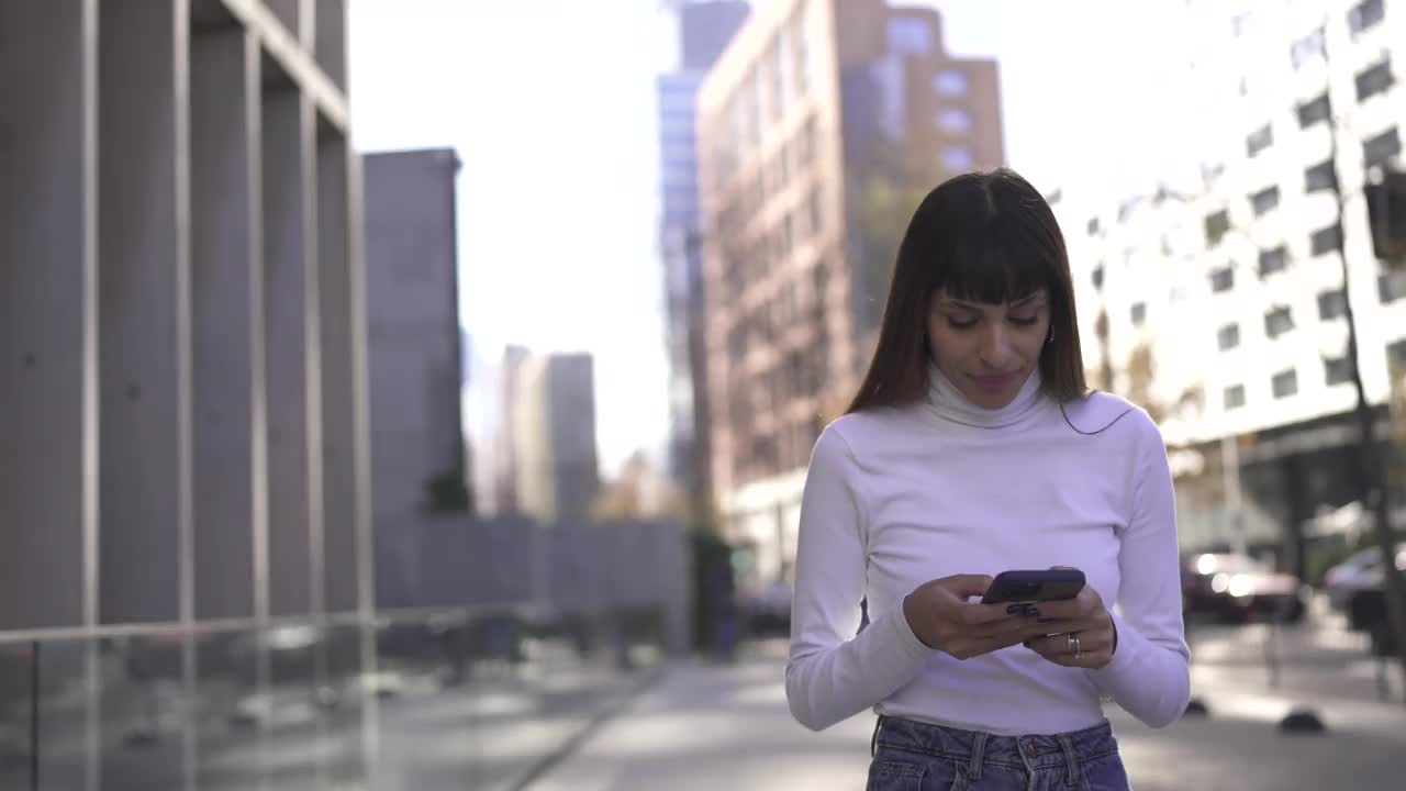 年轻女子在户外边走边用手机视频素材