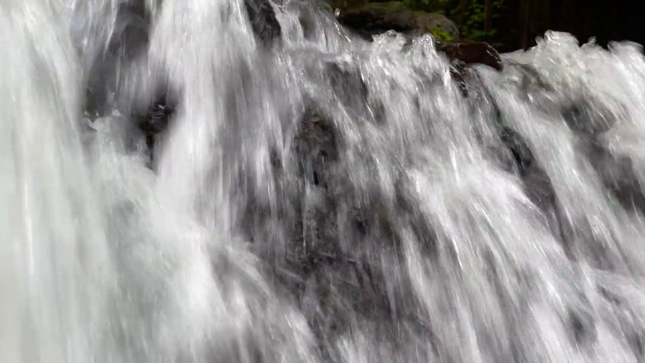 近距离观察瀑布在热带雨林的岩石上迅速流下。印尼巴厘岛乌布的Sumampan瀑布，4K视频。视频素材