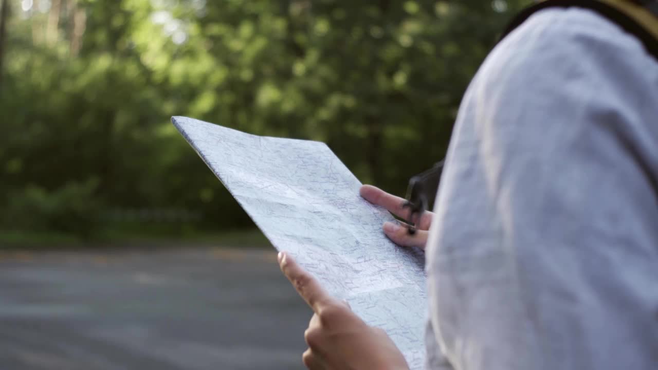 一个旅游的女孩正在森林里徒步旅行，站在太阳对面，戴着一顶漂亮的大帽子，看着视频素材