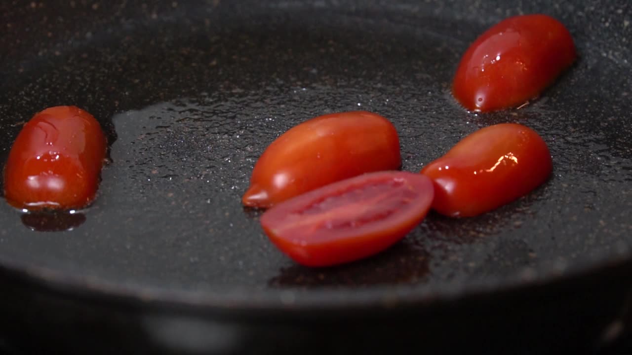 在平底锅里用油煎小圣女果。慢动作视频下载