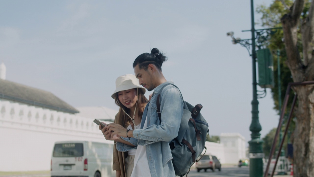 亚洲夫妇旅游检查地图的智能手机。视频素材