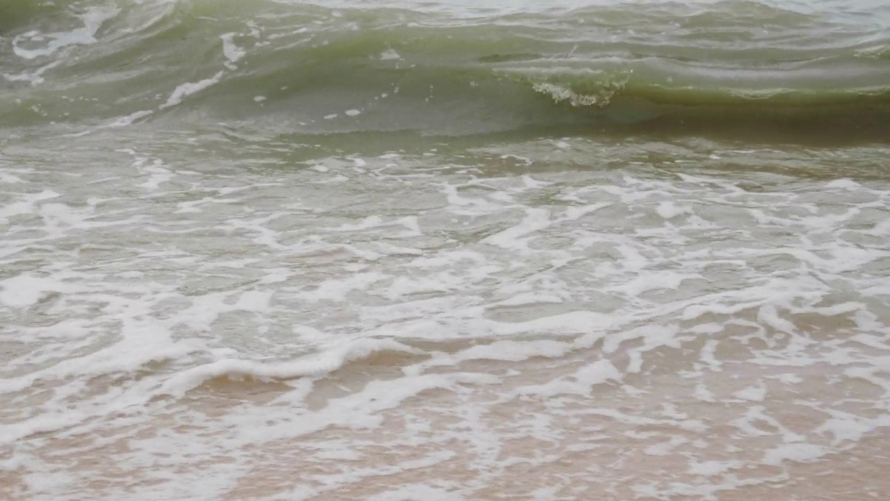 海滩上的慢动作泡沫波浪。雨后的海滩和雨季的巨浪视频素材