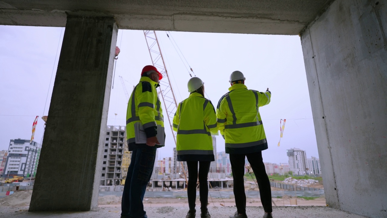 工头、女建筑师和建筑检查员正在检查施工现场，后视图视频素材