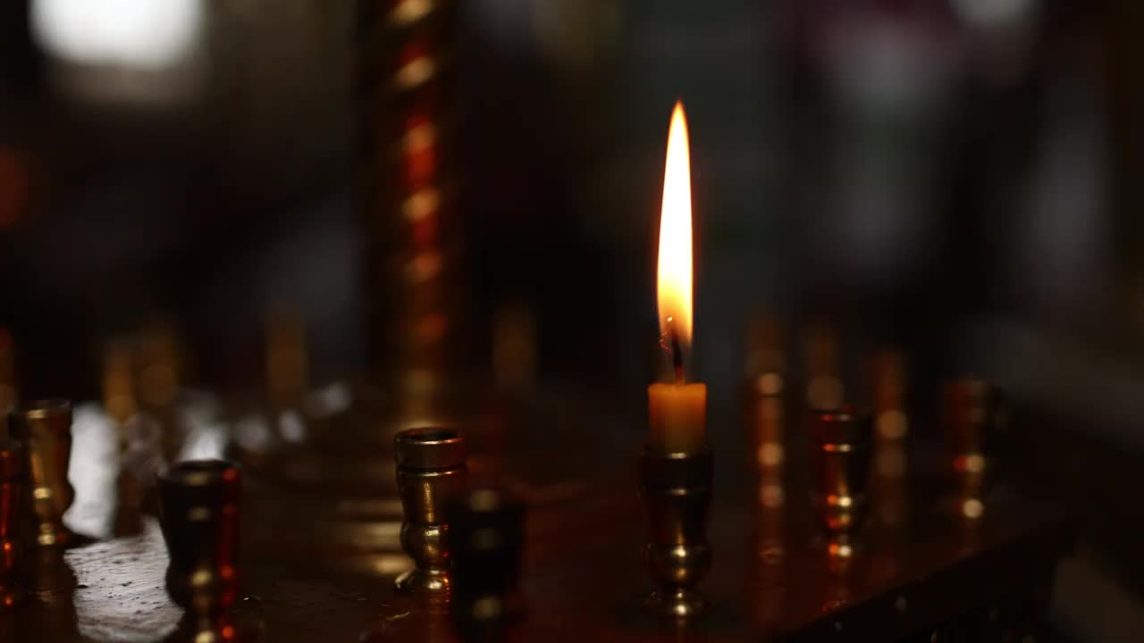 东正教教堂的最后一支蜡烛。教堂里的蜡烛在一个大的金色烛台上燃烧。视频素材