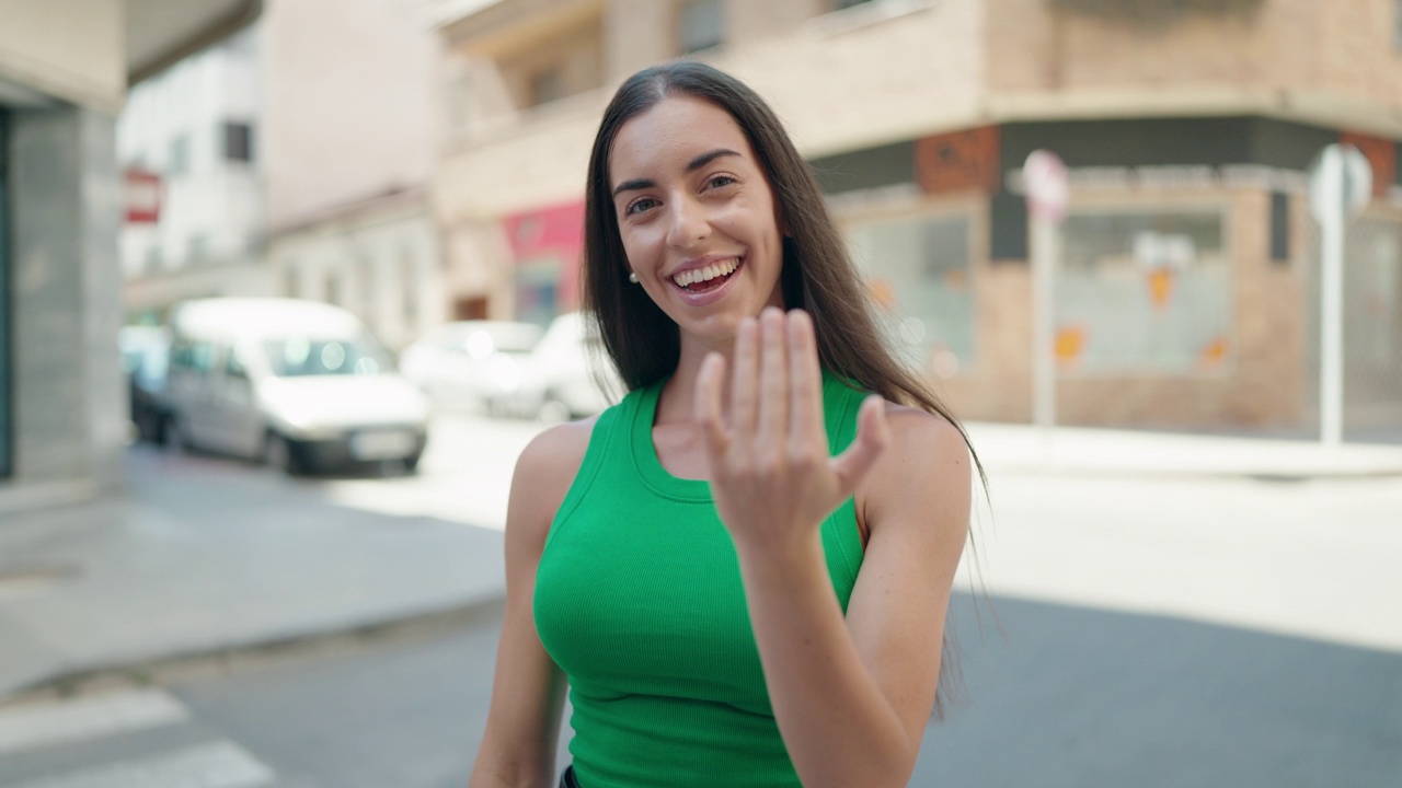 年轻美丽的西班牙女人微笑着自信地在街上用手做手势视频素材