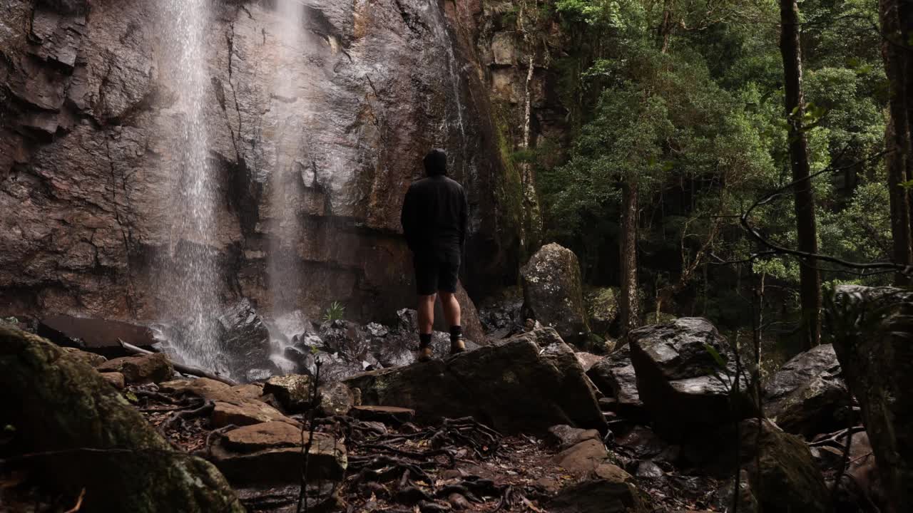 徒步旅行者欣赏宁静的瀑布在隐秘的雨林在4K慢动作视频素材