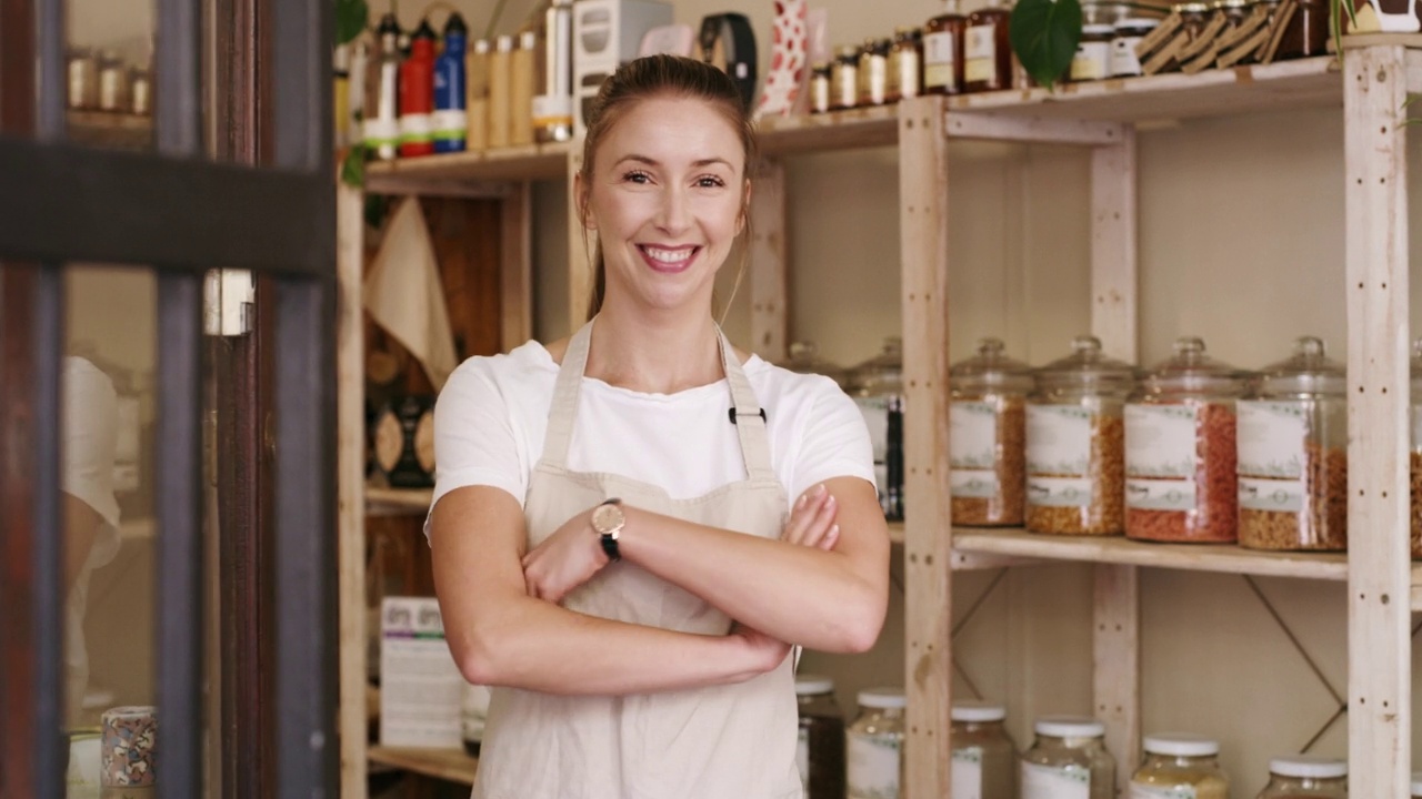 自信的年轻女店主为生意敞开大门。一家食材店的女企业家，微笑着独自在零售创业中取得成功。视频素材