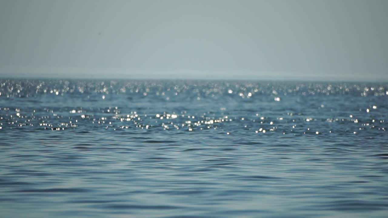 抽象海洋夏季海洋日落自然背景。小波浪水面上的运动模糊与金色的散景灯从太阳。度假、度假和休闲的概念。慢动作视频素材