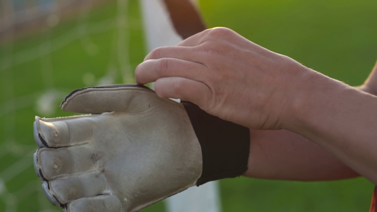 足球守门员戴着手套站在足球场的特写。缓慢的运动。视频素材